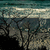 Pixelated static image showing a dark, abstract landscape with muted teal and gray tones against a lighter sky background.