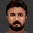 Pixelated static image of a person with short dark hair, light skin tone, and facial hair against a solid gray background.