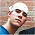 Static pixelated image of a person wearing a white head covering and blue clothing against a blurred background.