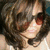A pixelated close-up of a person with dark curly hair, light skin tone, and visible facial features including eyes, nose, mouth, and cheeks.
