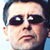 Pixelated close-up of a person's face with dark hair, large eyes, and neutral expression on light background.