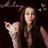Pixelated image of a person with long brown hair holding a white cat against dark background with faint pink floral shapes.