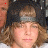 repeated identical images showing a person with light brown curly hair wearing a dark cap and gray headband, with small red heart symbols in the top-right corner