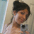 A pixelated image of a person with dark hair in a bun holding a camera, with text reading 'im', 'still', and 'smiling' below.