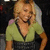 A woman with blonde hair wears a green and black dress, smiling with hands on hips in a static pose.