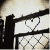 Black silhouette of a figure holding a long object with a heart shape formed by lines against a light background.
