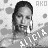Pixelated grayscale image of a person with long dark hair, wearing a light-colored top, with partial text 'AKO' and 'KEYS' visible in the background.