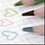 Six distinct heart-shaped icons in pastel colors arranged on a light background with partial dark shapes at top and bottom edges.