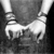 Black-and-white image of hands clasped in front, wearing multiple bracelets on both wrists.