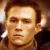 Pixelated close-up of a person's face with light brown hair, neutral expression, and warm-toned background.