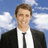 Pixelated image of a person in black suit and white shirt against blue sky with clouds, next to cyan text on solid blue background.