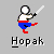 Pixelated character in martial arts pose holding a sword, wearing red and blue pants with white top against gray background.