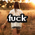 Pixelated image of a person in a white shirt and dark shorts walking away from the viewer toward a warm-toned background with brown and orange hues.