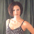 Static pixelated image of a person with short brown hair wearing a sleeveless patterned top against a dark vertical striped background.