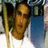 Pixelated static image of a person with long brown hair holding a golden staff, wearing dark clothing against a blue and white background.