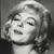 Black-and-white pixelated portrait of a person with closed eyes, styled hair, and a visible earring against a dark background.