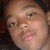 Pixelated close-up of a person's face with light skin tone, dark hair visible at top right, and pink lips showing slight smile.