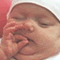 A close-up of a person's face with closed eyes, hand covering mouth in a gesture of laughter or surprise.