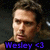 Pixelated portrait of a person with light brown hair and fair skin, wearing dark clothing against a blurred background with blue text overlay reading "Wesley <3".