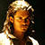 Pixelated static image of a person with light brown hair and orange-toned skin against dark background, wearing white clothing with visible shoulder details.