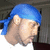 A person wearing a blue bandana and white shirt appears in four showing slight head movement against a dark background
