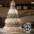 Animated sequence showing a three-tiered cake with a pointed top, partially obscured by a circular clock-like icon on the right side.