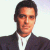 Pixelated portrait of a person with short dark hair wearing a dark jacket over a white shirt against a light background.