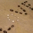 A static image of a light brown textured background with scattered dark brown and white pixel clusters arranged in horizontal lines.