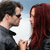 Two people face each other in profile, one with dark hair and sunglasses, the other with long red hair, against a light blue sky background.
