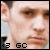 A pixelated close-up of a person's face with visible eyes, nose, and mouth; the lower-left corner shows "<B GC" text.