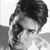 Black-and-white pixelated static icon of a person's head and shoulders with dark hair, visible facial features including eyes and nose, and partial shoulder/neck area against a light background.