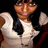 Pixelated image of a person with light brown skin wearing a white sleeveless top and dark tie, arms raised in a celebratory pose against a black background.