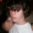A pixelated image of a person with curly hair wearing a white shirt, accompanied by orange text on a dark red background.