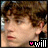 16 identical pixelated frames showing a person with brown curly hair and light skin, each frame containing pink and white text elements at the bottom