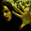 A person with dark hair holds up a hand in front of a wall covered in black graffiti-style text on a yellow background.