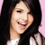 A person with long dark hair and a white top smiles against a pink background, with visible pixelation and slight variations in head position across frames.