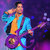 Pixelated figure in blue and orange attire holding a long object against a purple and blue gradient background.