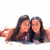 Two people with long dark hair lie side-by-side on a light surface, facing forward with neutral expressions.