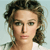 Pixelated portrait of a person with light skin tone, brown curly hair, and neutral expression against light blue background.