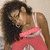 A person with curly dark hair wearing a pink and white top, shown in four with slight head and shoulder movements