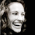 Pixelated grayscale image of a person's face with closed eyes and a broad smile, set against a solid black background.