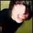 Pixelated image of a person with dark hair and black clothing against green background, overlaid with white text on black.