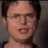 A pixelated image of a person with dark hair and glasses, wearing a black top against a gray background.