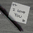 A static image shows a handwritten note reading 'I Love You' next to a pen on a textured surface.
