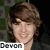 A pixelated image of a person with light brown hair and blue eyes, wearing dark clothing against a green-patterned background.