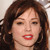 Pixelated close-up of a person with brown hair, red lips, and a neutral expression against a light background.