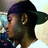 Pixelated static image of a character with dark hair and green clothing in profile view against a light background.