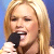 Static 50x50 pixel icon showing a close-up of a person with long blonde hair holding a black microphone against a blue background.