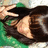 Pixelated static image shows a person with dark hair and light skin wearing a black top against green background.