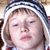 A static image of a person with light brown hair wearing a striped knit hat and red-and-white checkered clothing.